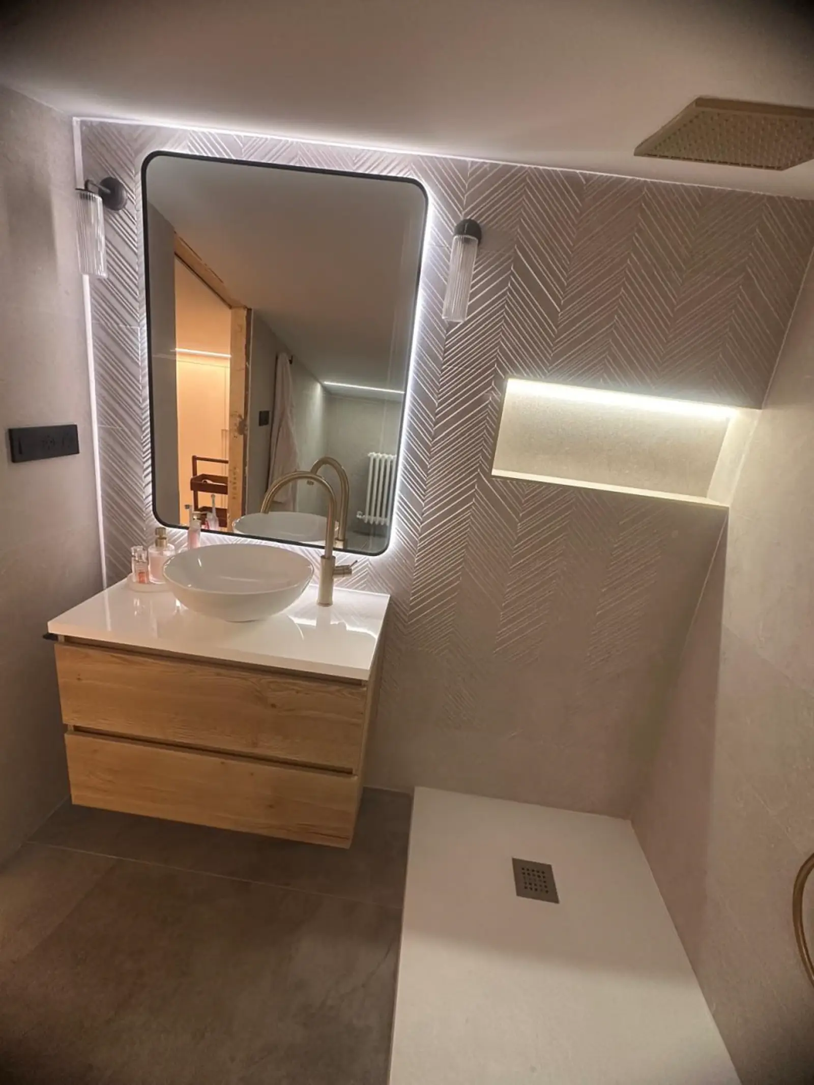 Detalle de baño reformado con espejo iluminado, hornacina y lavabo sobre encimera